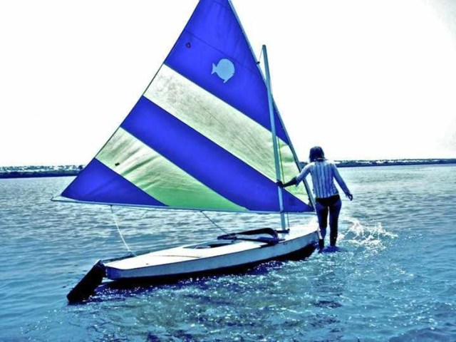Walking a sunfish over a sandbar in salt run the summer a taught youth sailing. 